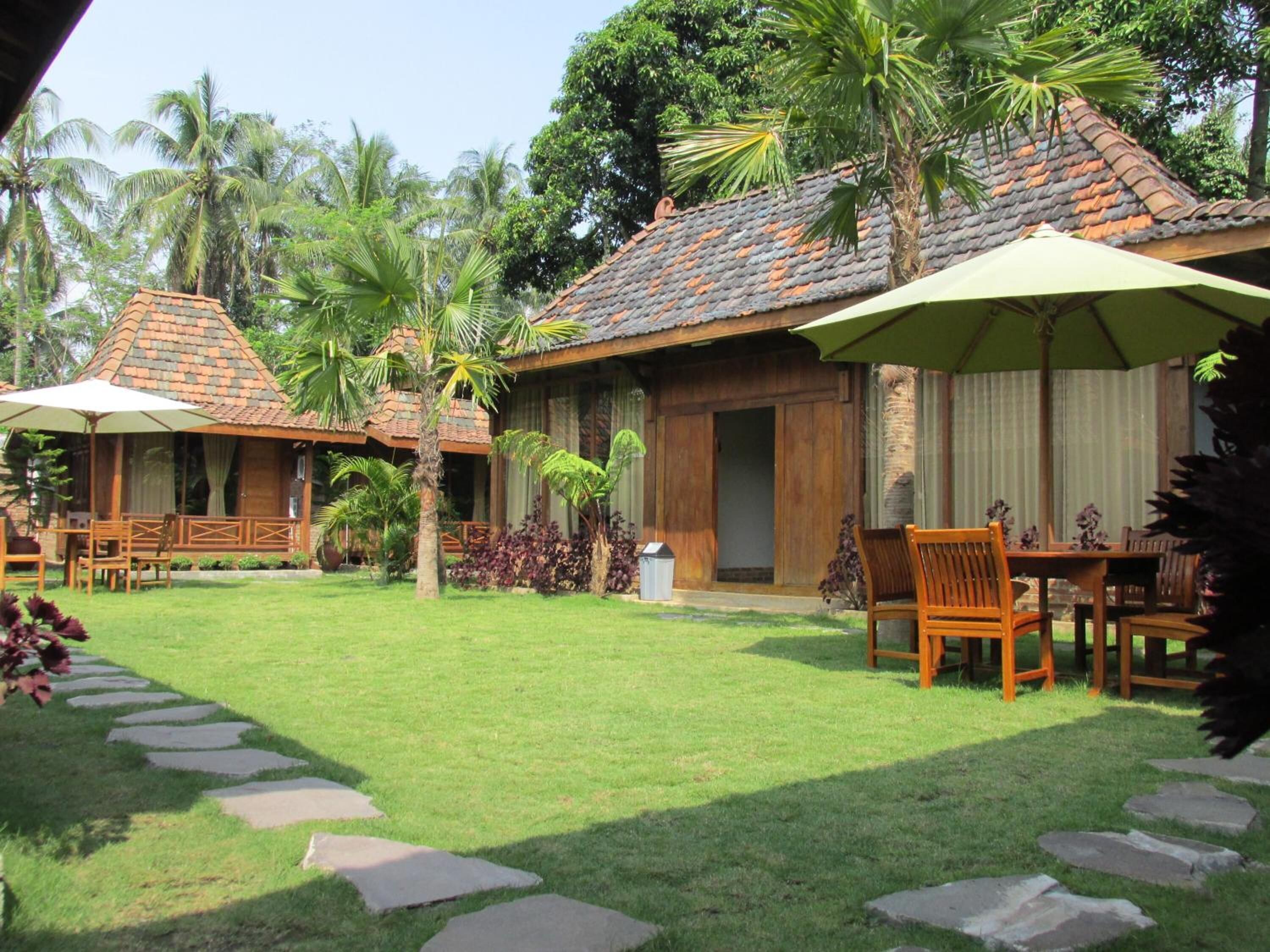 A bungalow with a tiled roof, wooden furniture, and a stone pathway.