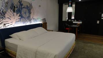 Una habitación de hotel con una cama grande, un escritorio con una silla y un mural en la pared.