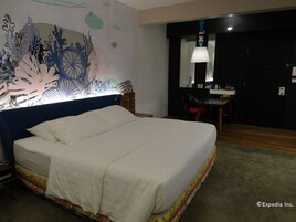 Una habitación de hotel con una cama grande, un escritorio con una silla y un mural en la pared.