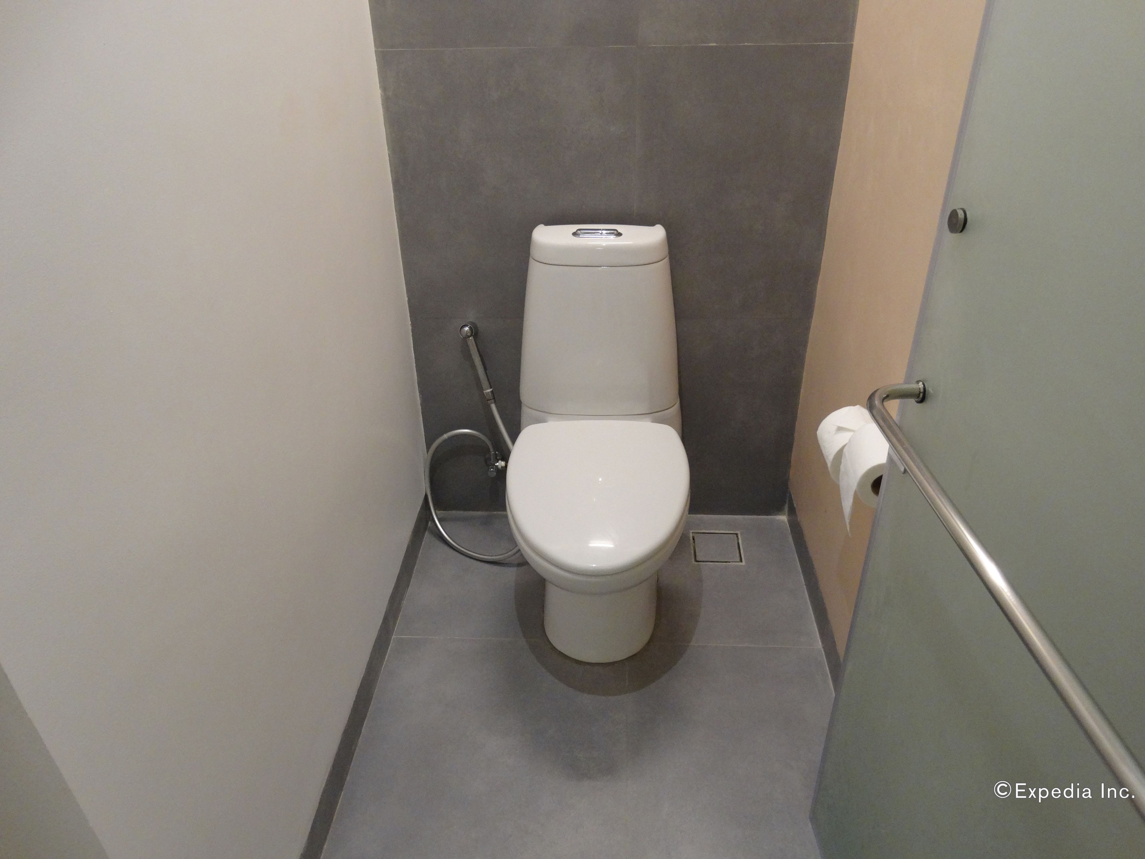 A modern bathroom with a toilet, a hand dryer, and a paper towel dispenser.