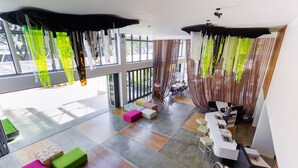 Um espaço de escritório moderno com grandes janelas, decorações penduradas coloridas e diversas opções de assento.