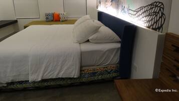 A bedroom with a bed, a headboard, a nightstand, and a wall with a decorative pattern.