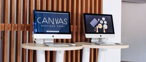 Dos monitores de computadora sobre una mesa con un panel de madera de listones al fondo.