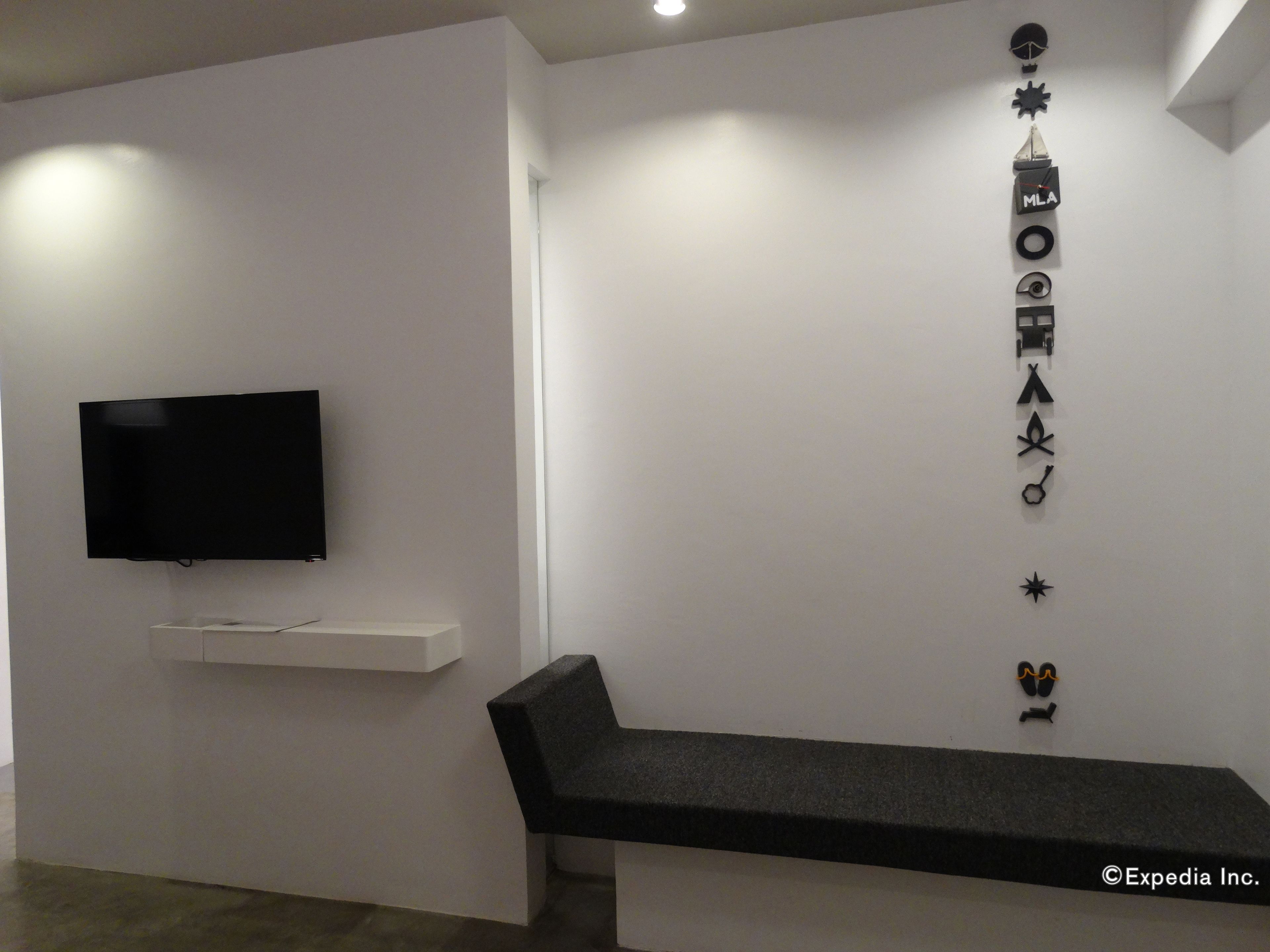 A modern room with a flat-screen TV mounted on the wall, a bench, and a wall with various black decorative items.