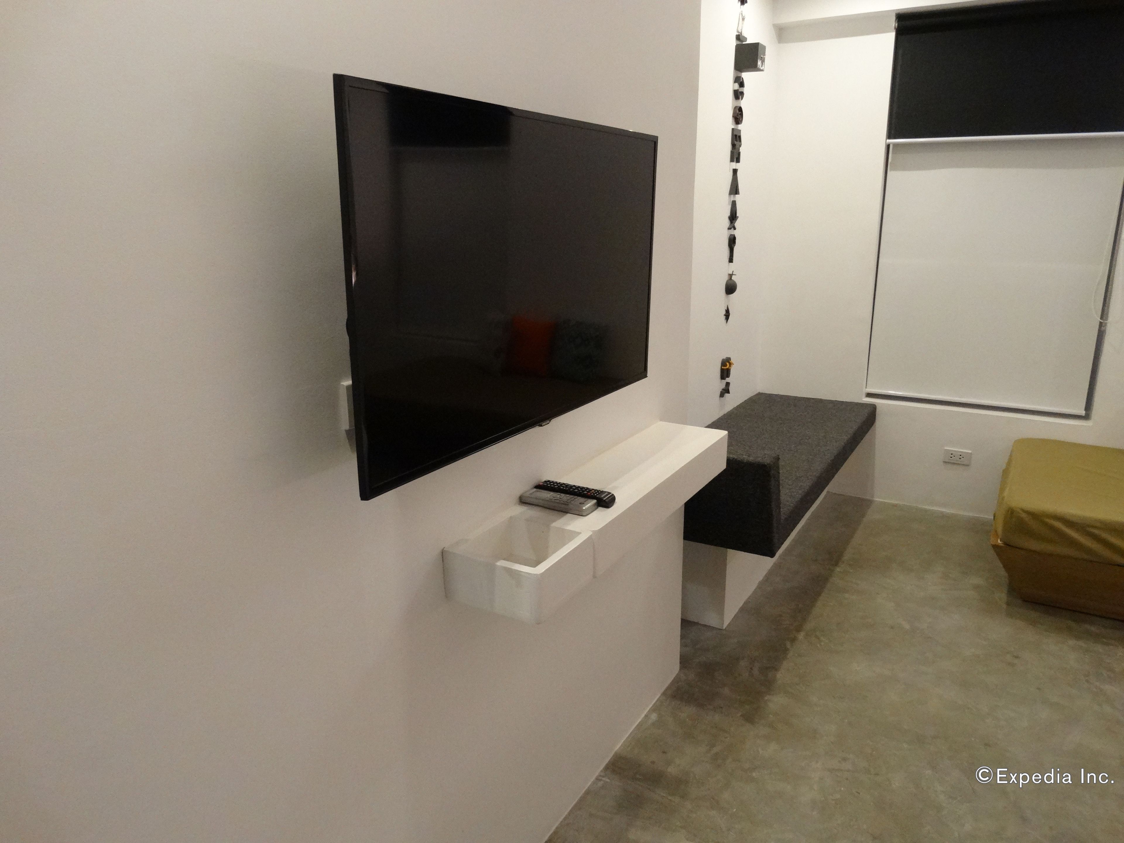 Ein modernes Badezimmer mit einem großen Spiegel, einem integrierten Fernseher, einem weißen Waschtisch und einer Bank.