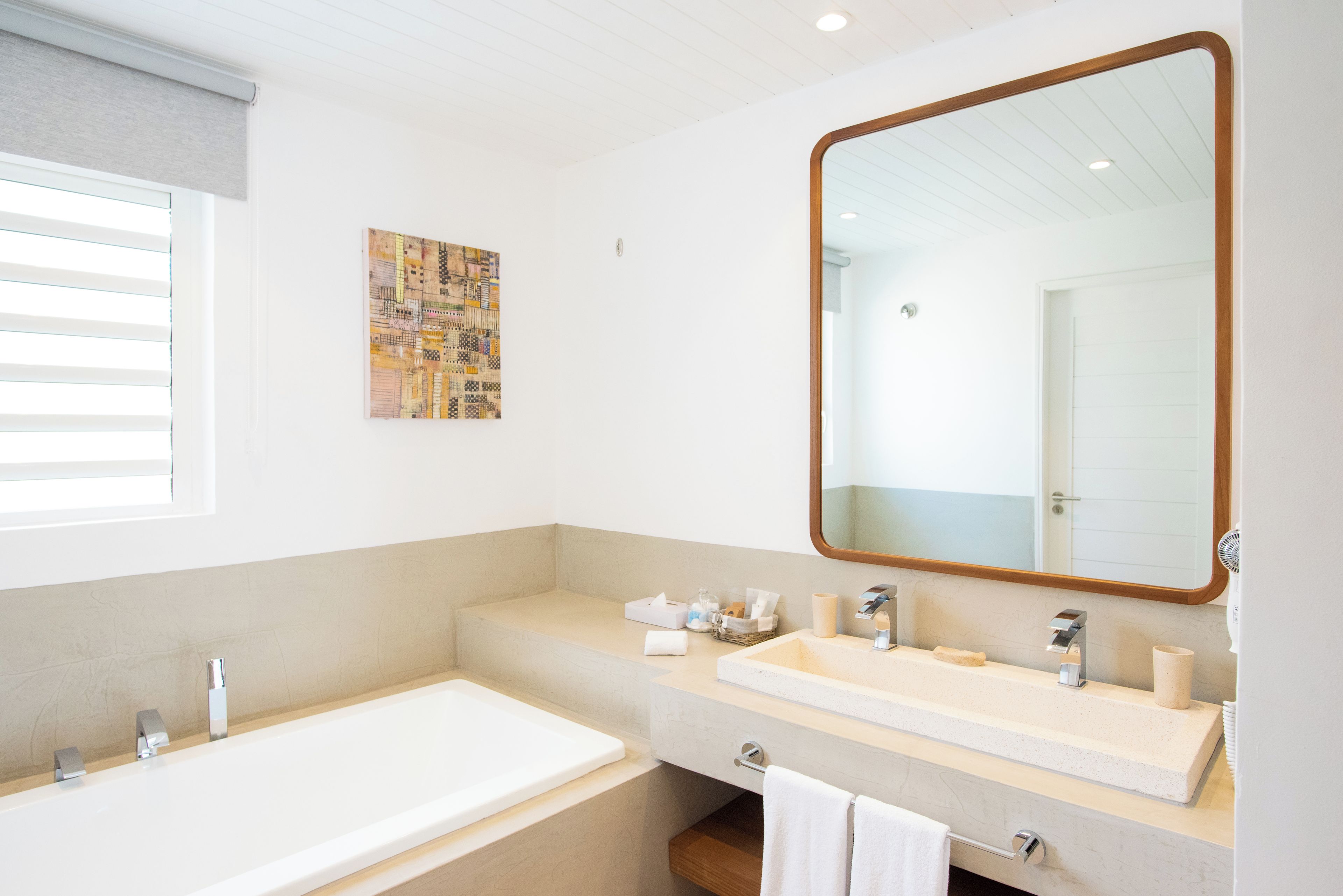 A modern bathroom with a large mirror, a bathtub, and a vanity with a sink.