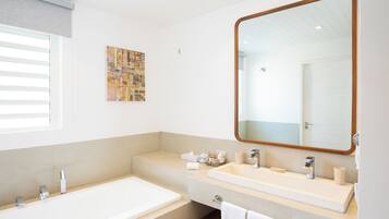 A modern bathroom with a large mirror, a bathtub, and a vanity with a sink.