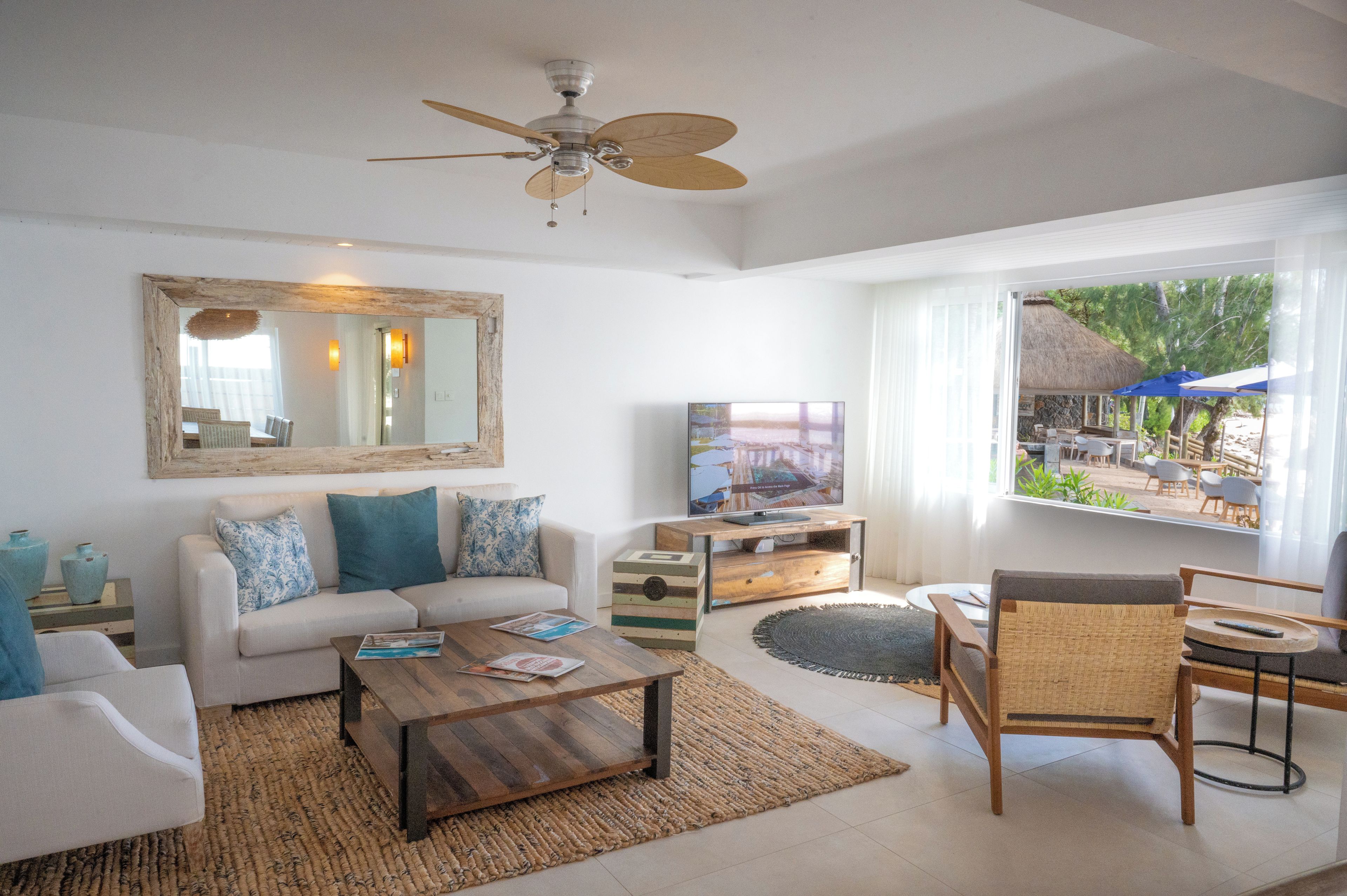 A living room with a sofa, coffee table, TV, and a view of an outdoor area.