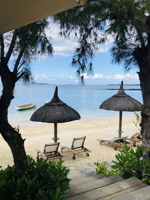 Di pantai, pasir putih, kerusi lepak pantai, payung 