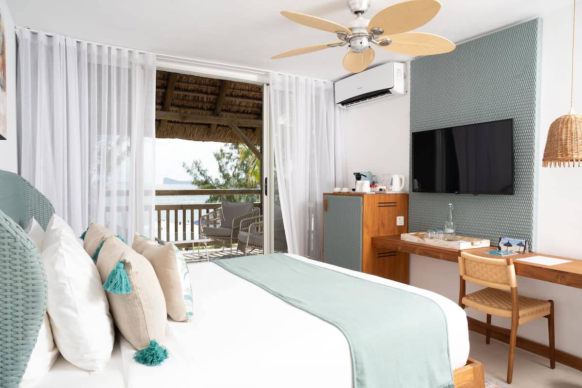 Een slaapkamer met een bed, een bureau, een stoel, een televisie en een balkon met uitzicht.