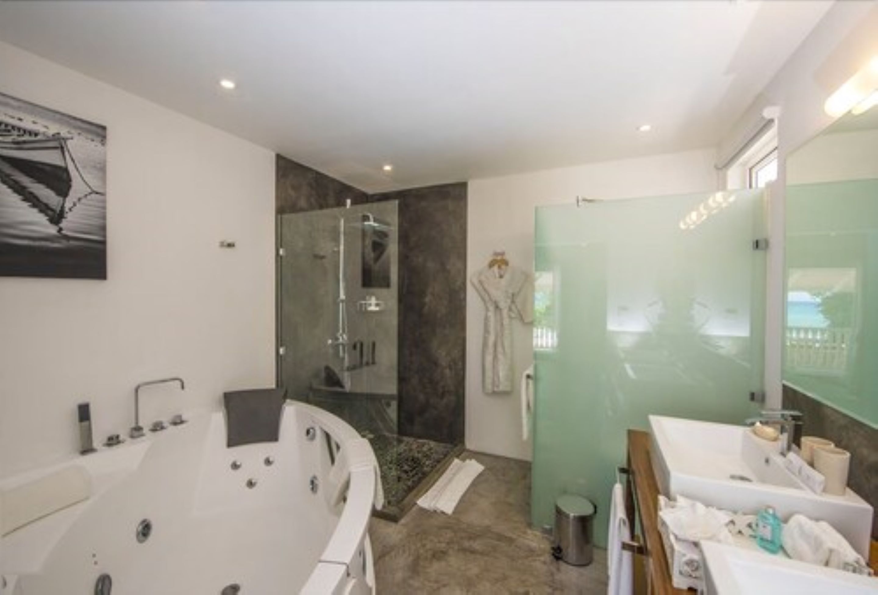 Un baño moderno con una bañera independiente, ducha con mampara de vidrio y tocador con espejo.