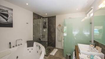 Un baño moderno con una bañera independiente, ducha con mampara de vidrio y tocador con espejo.