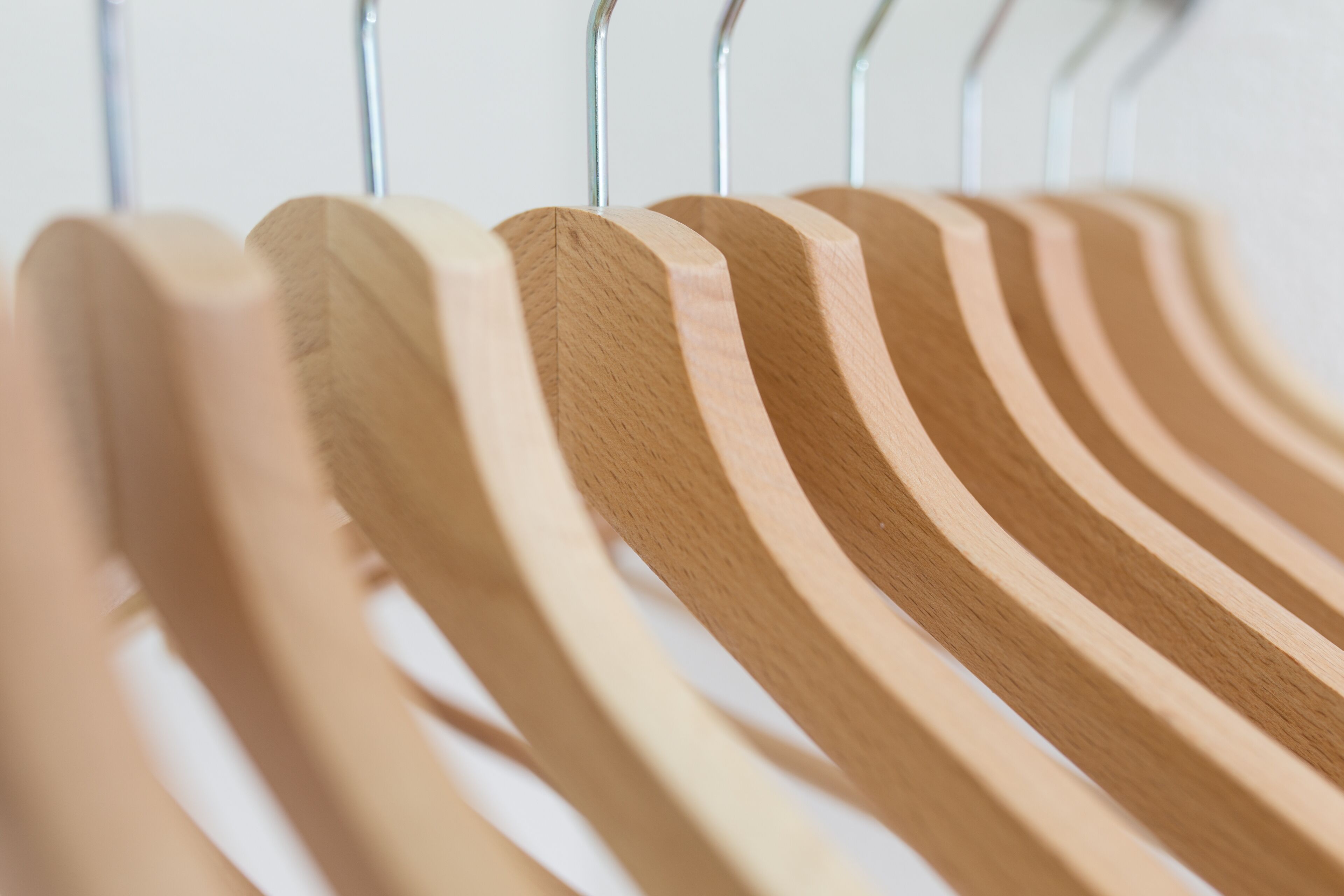 A close-up of wooden hangers on a metal rack.