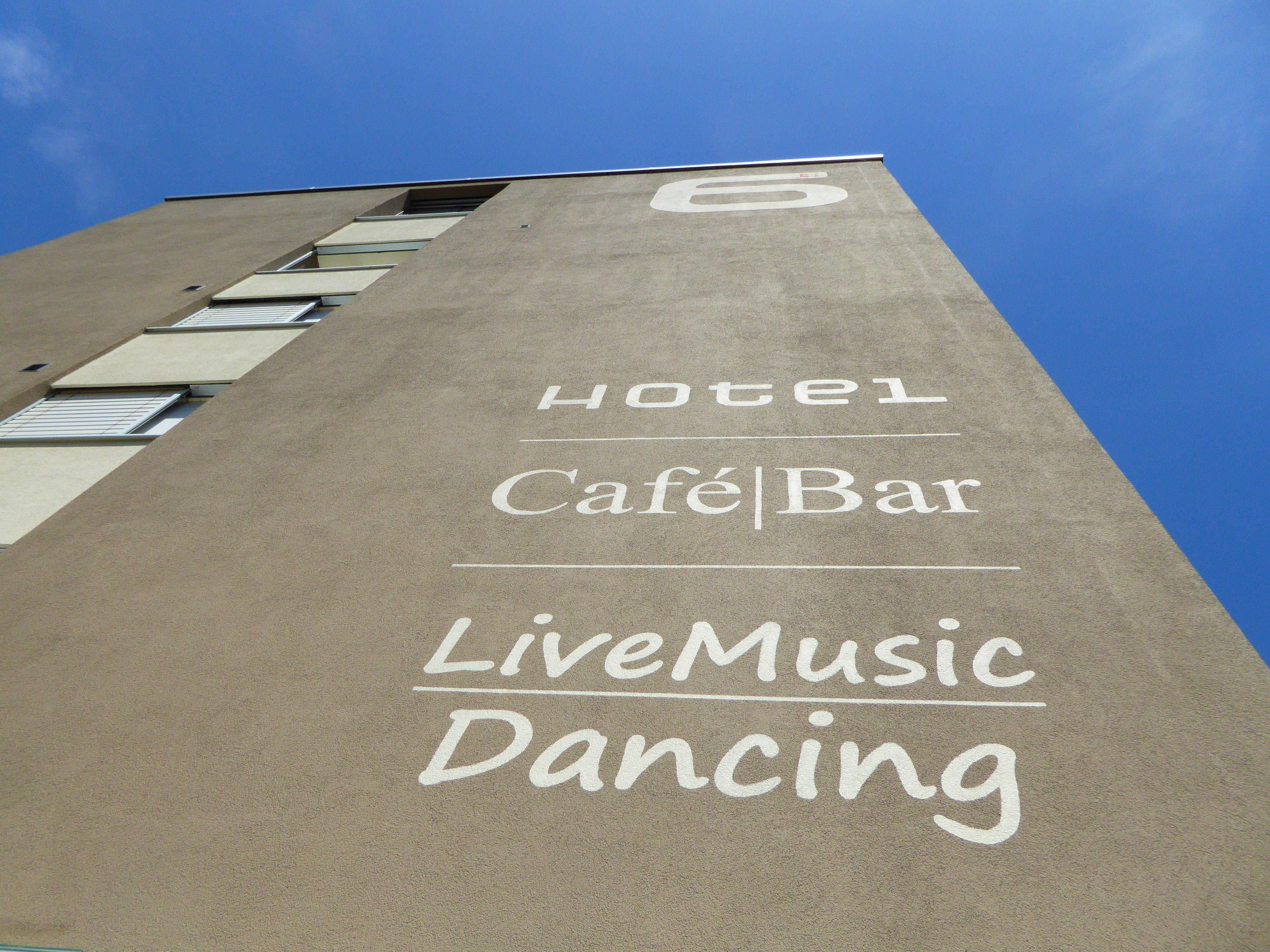 A building with a sign indicating a hotel, café, bar, live music, and dancing.