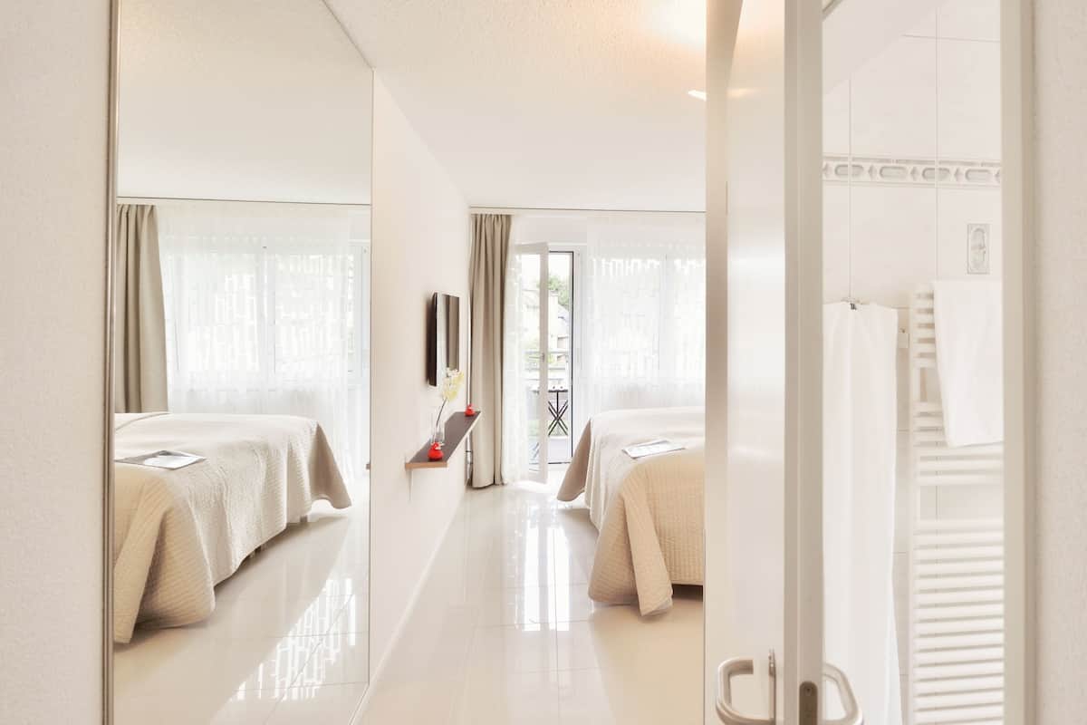 Quarto de hotel com duas camas, banheiro e vista para o exterior.