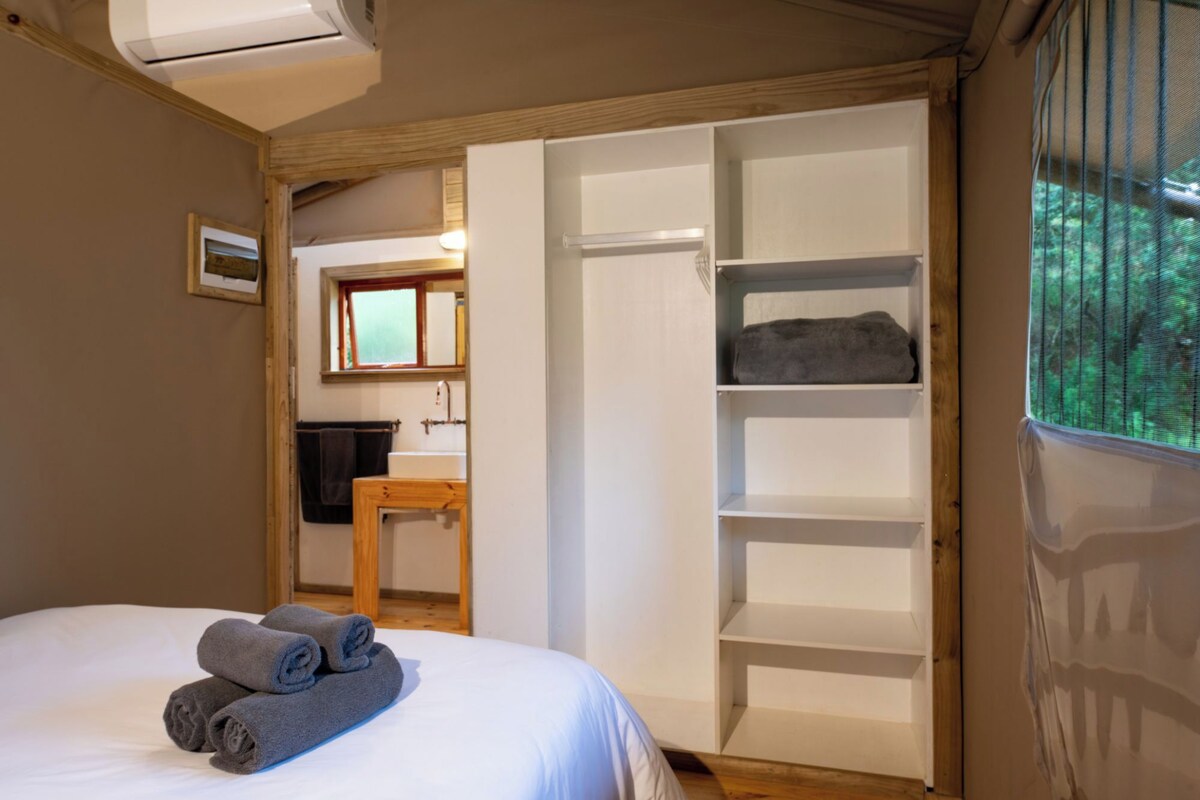 Een slaapkamer met een bed, een houten bureau, een raam en een kledingkast.