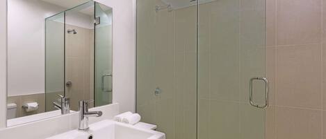 A modern bathroom with a glass-enclosed shower, a white sink, and a large mirror.
