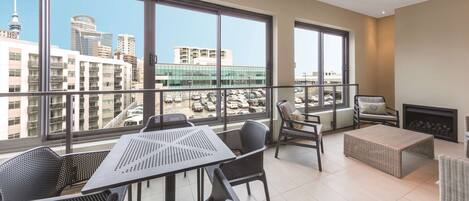 A spacious balcony with a table and chairs, large windows offering a city view, and a fireplace.