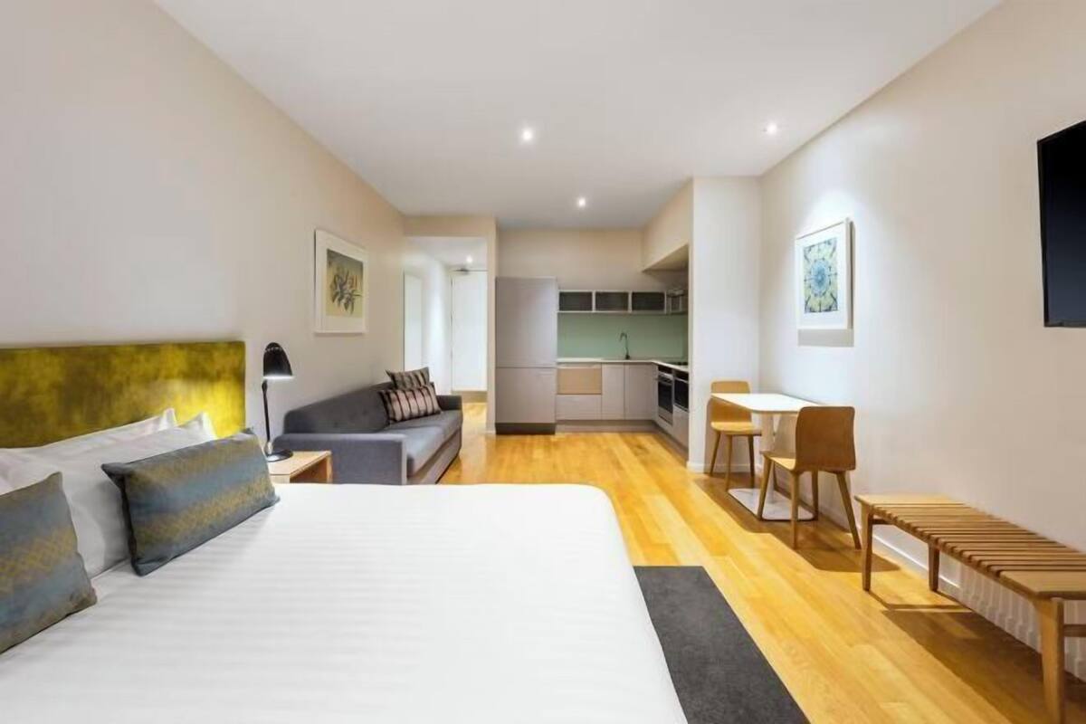 Ein modernes Hotelzimmer mit einem großen Bett, einer Couch, einem Schreibtisch und einer Küchenzeile.
