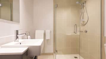 Ein modernes Badezimmer mit einer Duschkabine, einem weißen Waschbecken und einer Toilette.