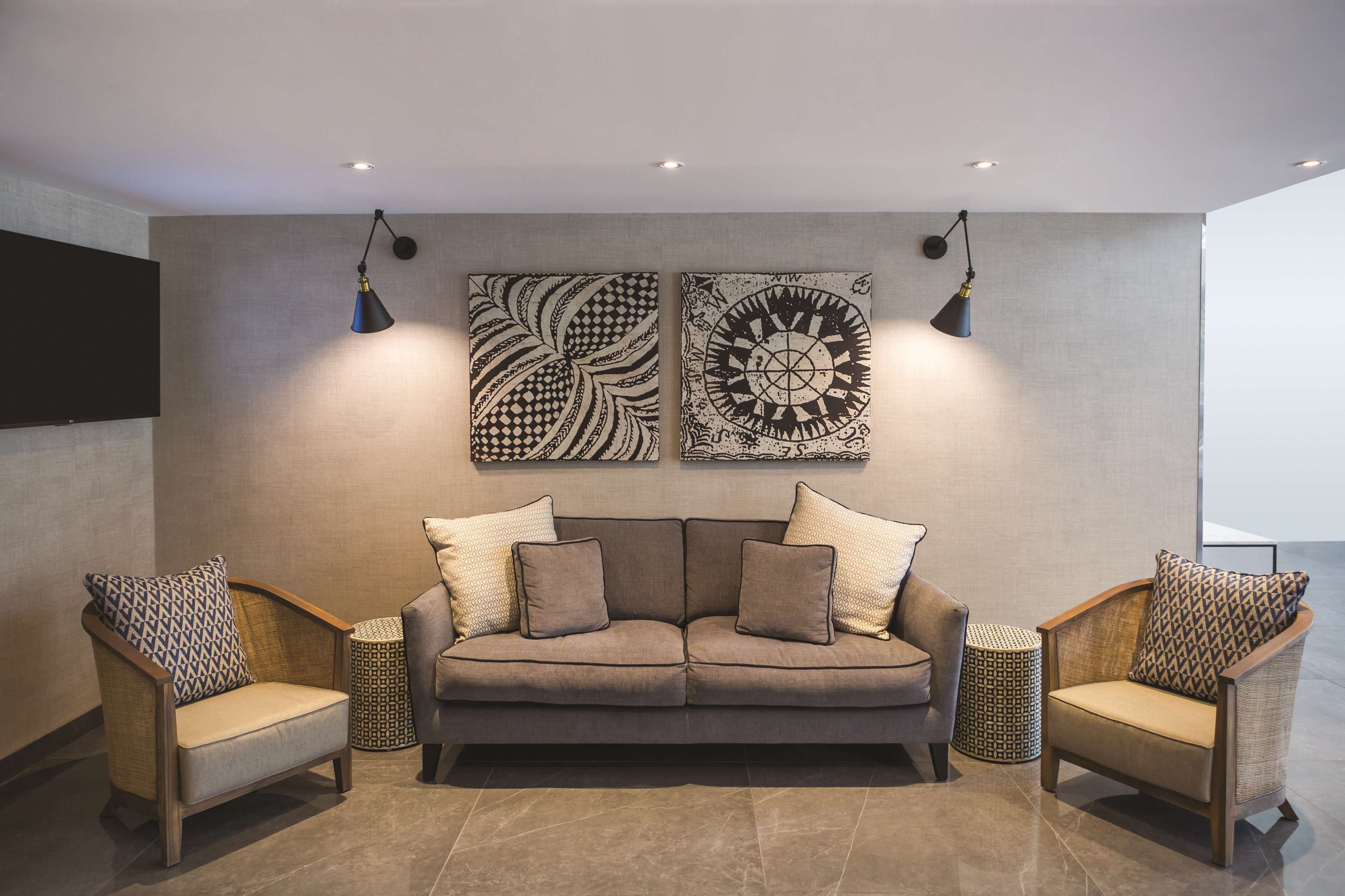 Ein modernes Wohnzimmer mit einem grauen Sofa, zwei Sesseln und gemusterten Kissen.