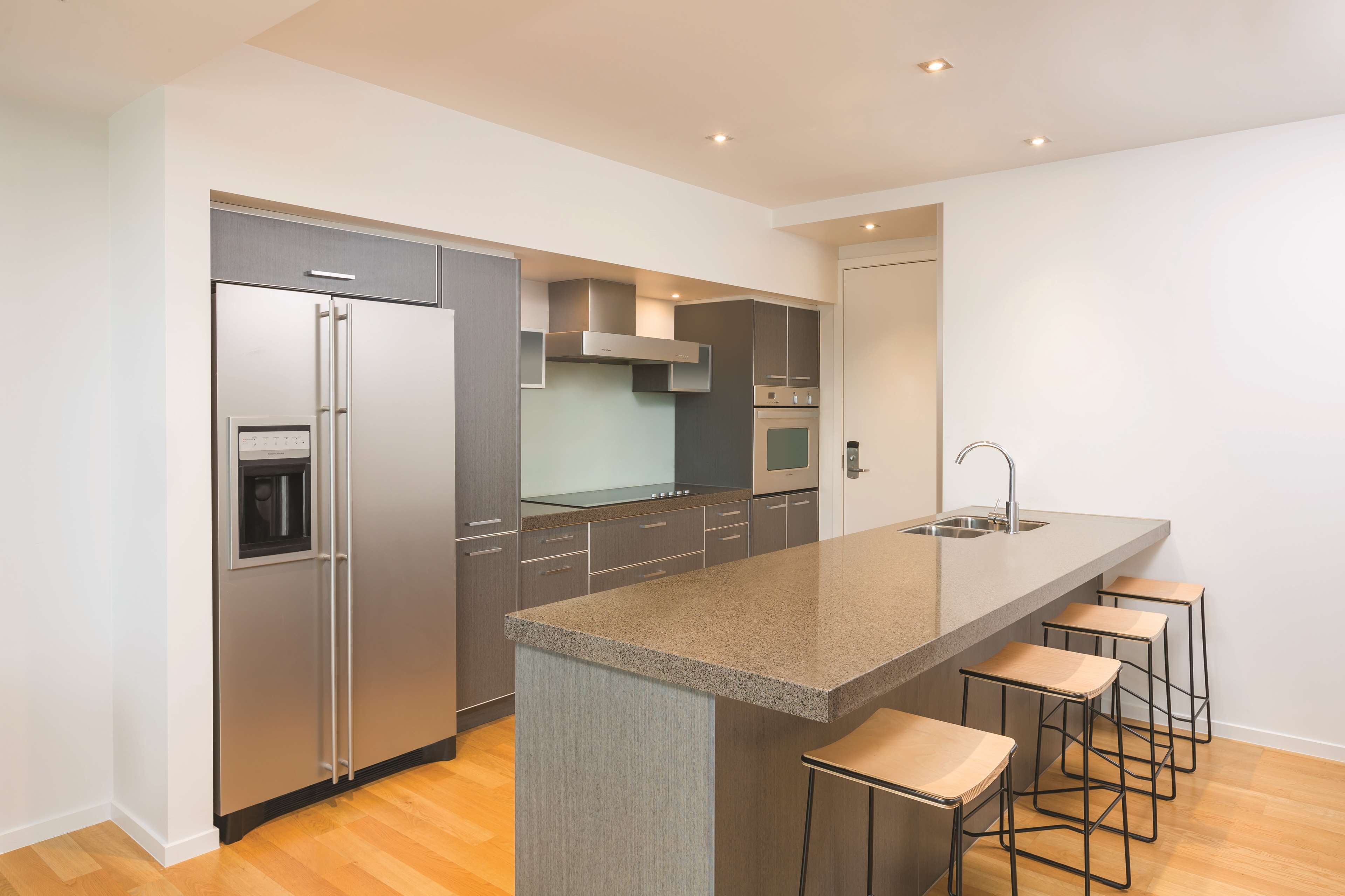 A modern kitchen with a central island, stainless steel appliances, and bar stools.