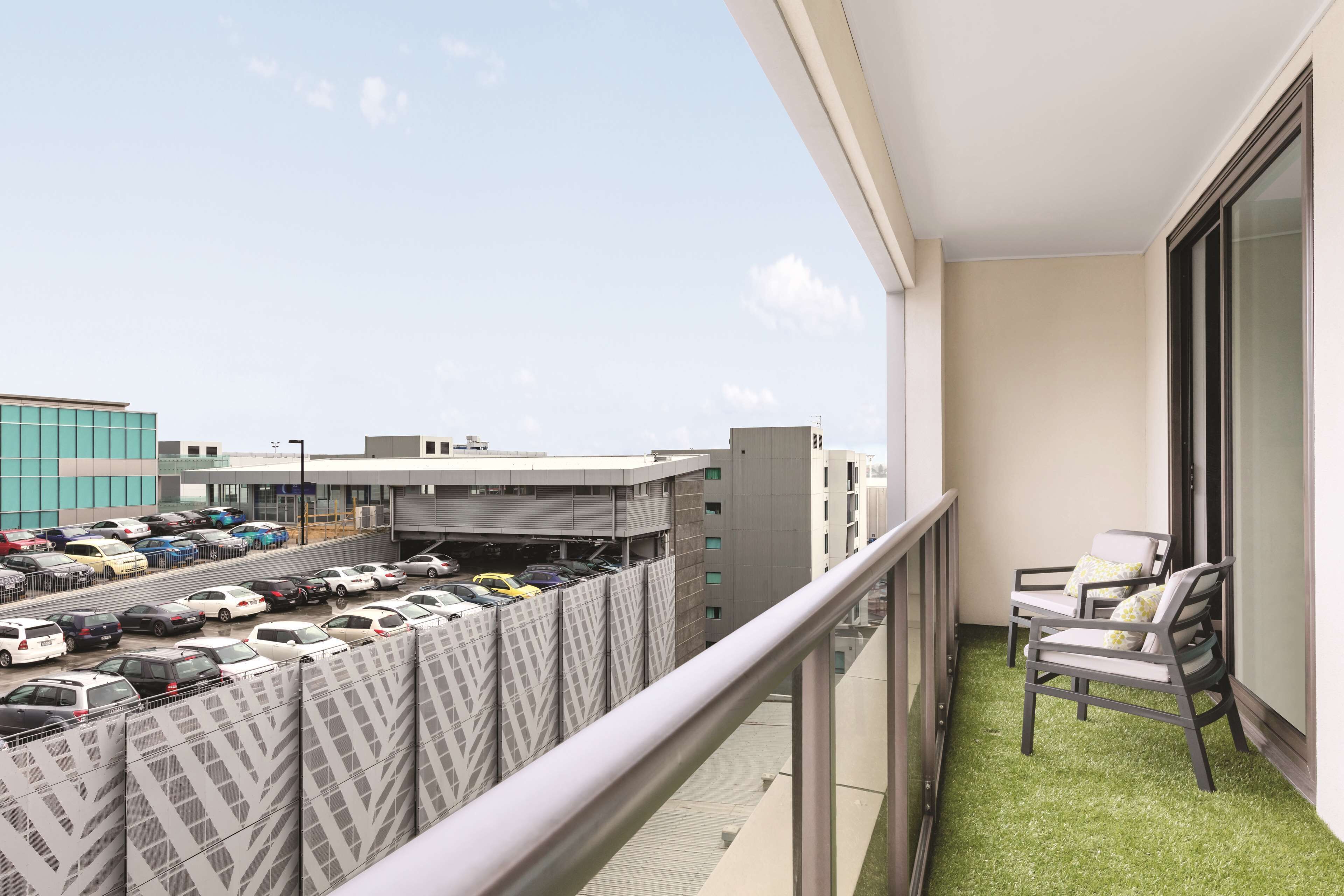 Un balcon donnant sur un parking et des immeubles.