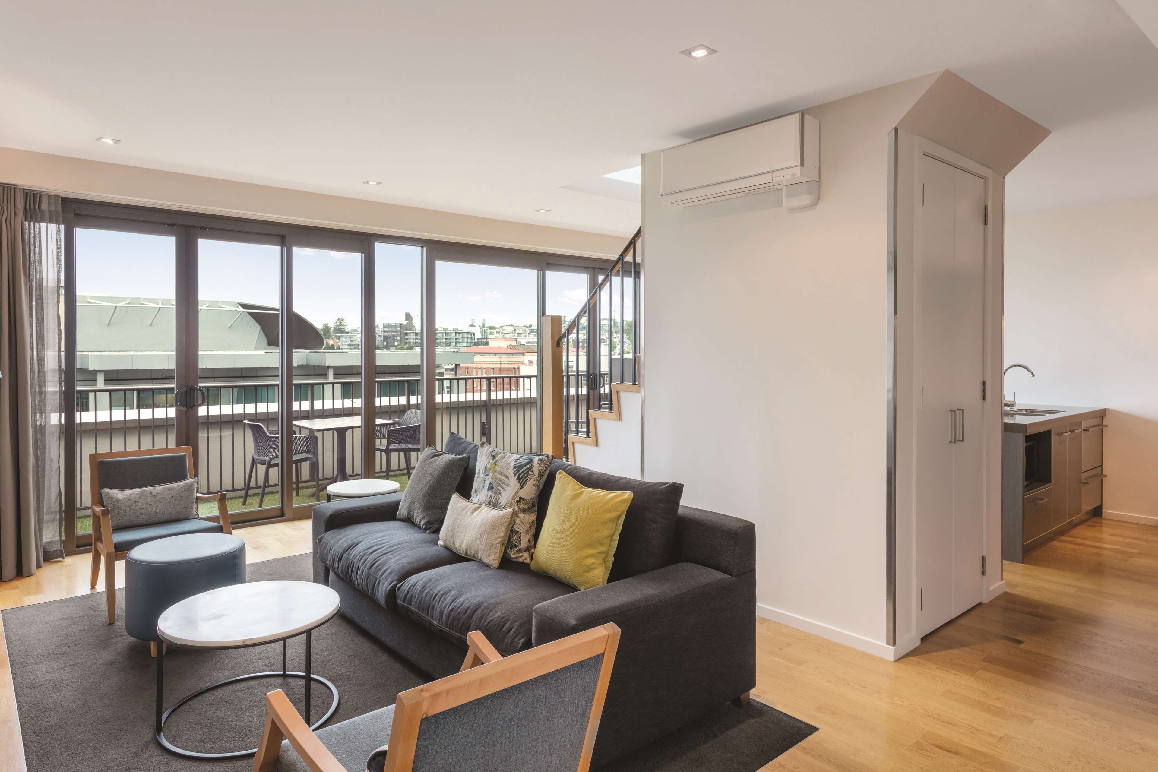 Un appartement moderne doté d’un balcon, d’un canapé, d’une table à manger et d’un coin cuisine.