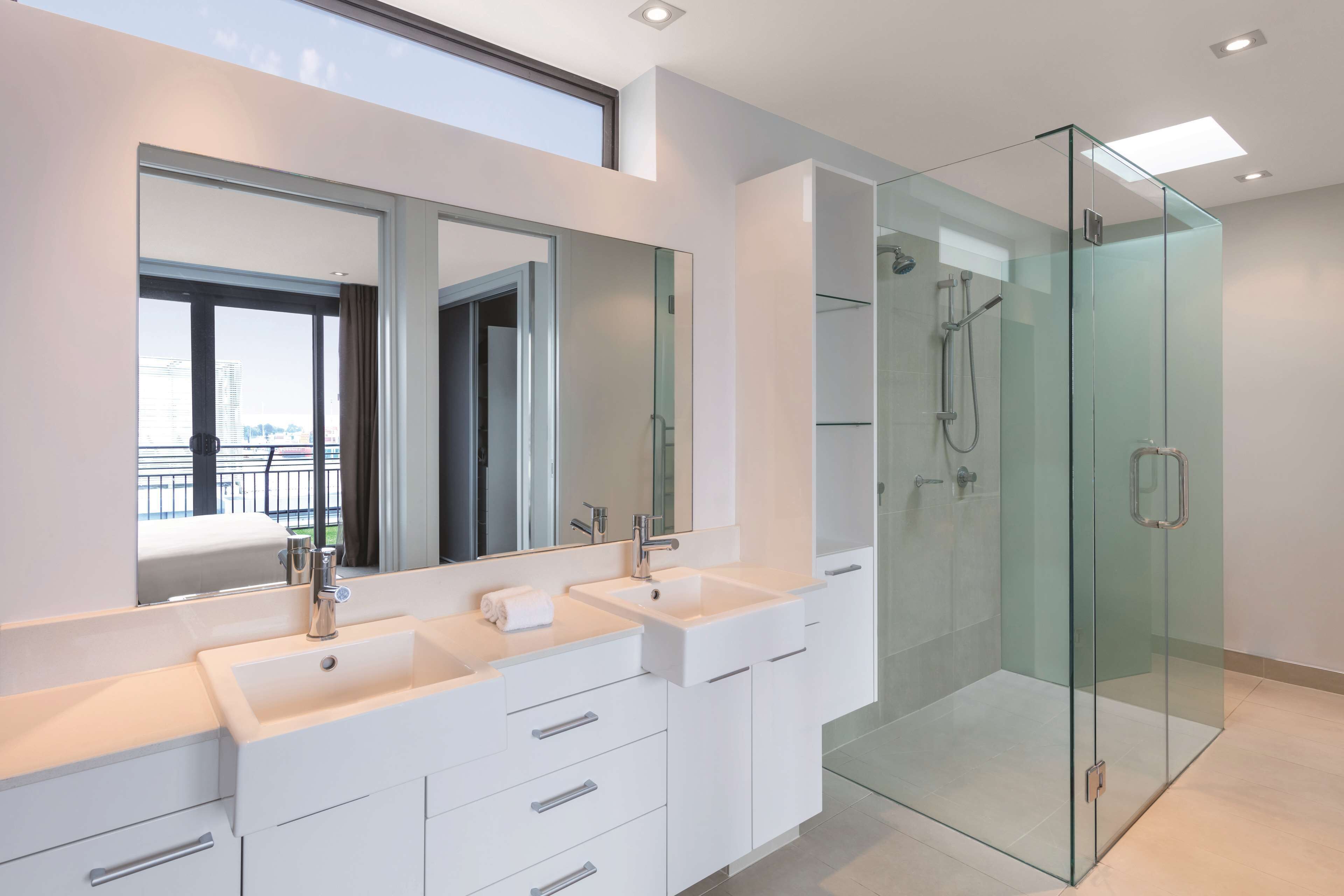 A modern bathroom with a glass-enclosed shower, a large mirror, and a dual sink vanity.