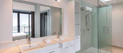 Une salle de bain moderne avec une douche à parois de verre, un grand miroir et un meuble-lavabo à deux vasques.