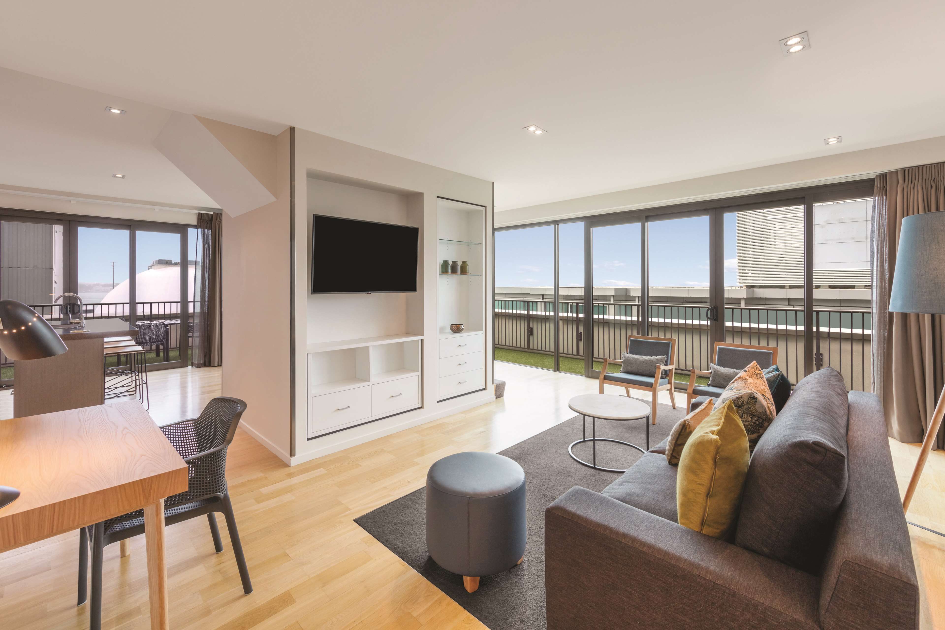 A modern living room with a sofa, ottoman, and dining area.