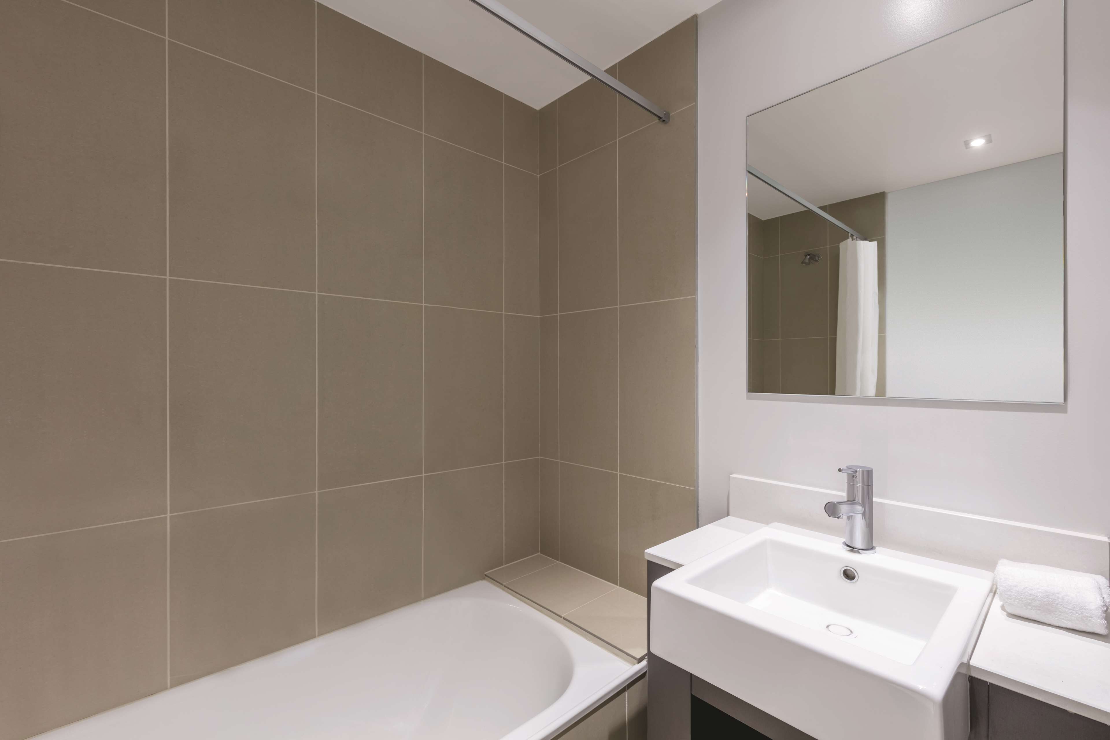 A modern bathroom with a bathtub, a sink, and a mirror.