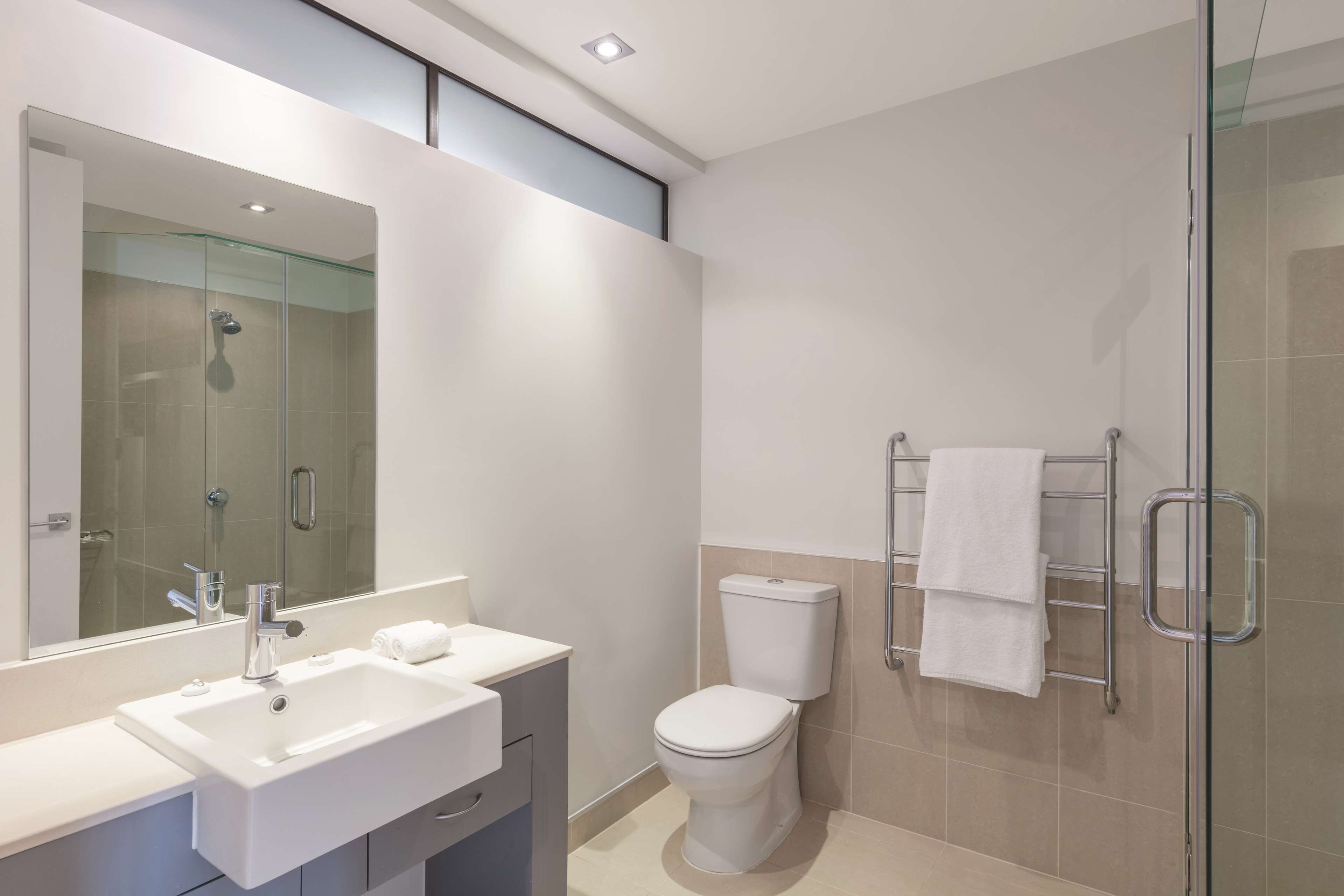 A modern bathroom with a glass-enclosed shower, a white sink, and a toilet.