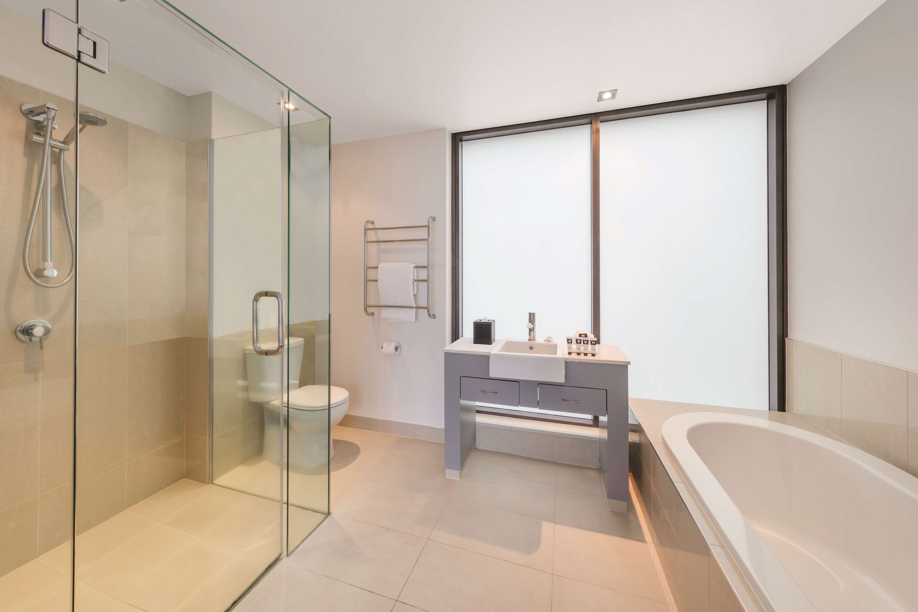 Un baño moderno con cabina de ducha de vidrio, inodoro, tocador con lavamanos y bañera.