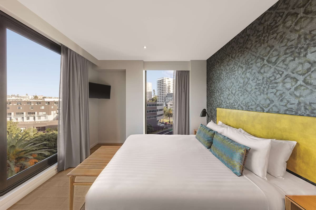 Ein Hotelzimmer mit einem großen Bett, Blick auf die Stadt und modernem Design.