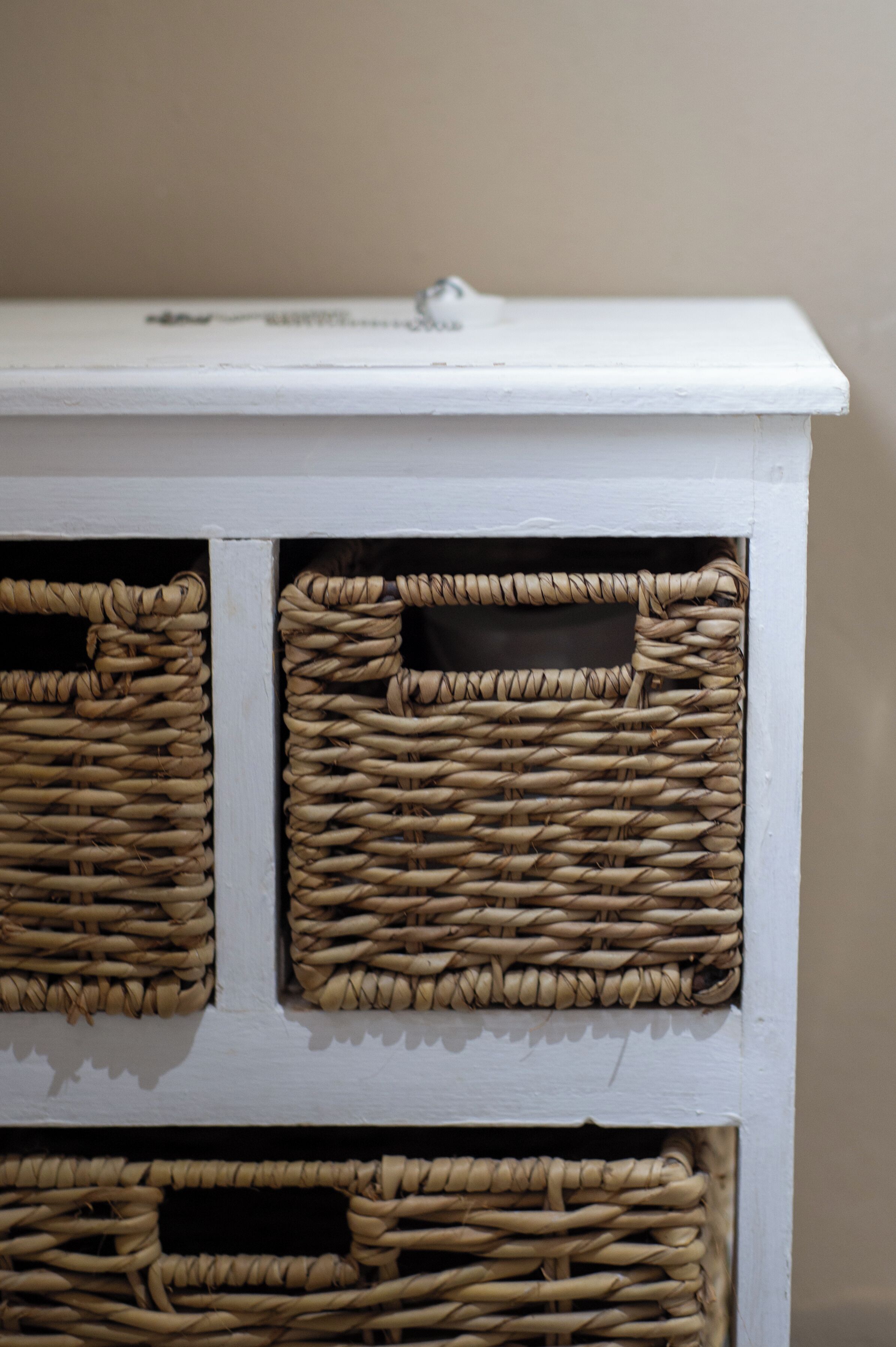A white storage unit with woven baskets.