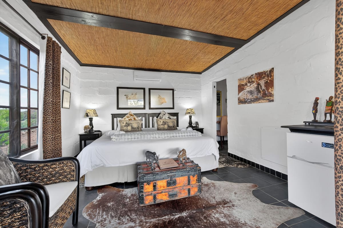 A bedroom with a large bed, a nightstand, a dresser, and a suitcase.