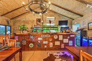 A rustic bar area with a wooden ceiling, a bar counter labeled 'MAN CAVE,' and various liquor bottles. - Zwartberg View Mountain Lodge (Oudtshoorn)