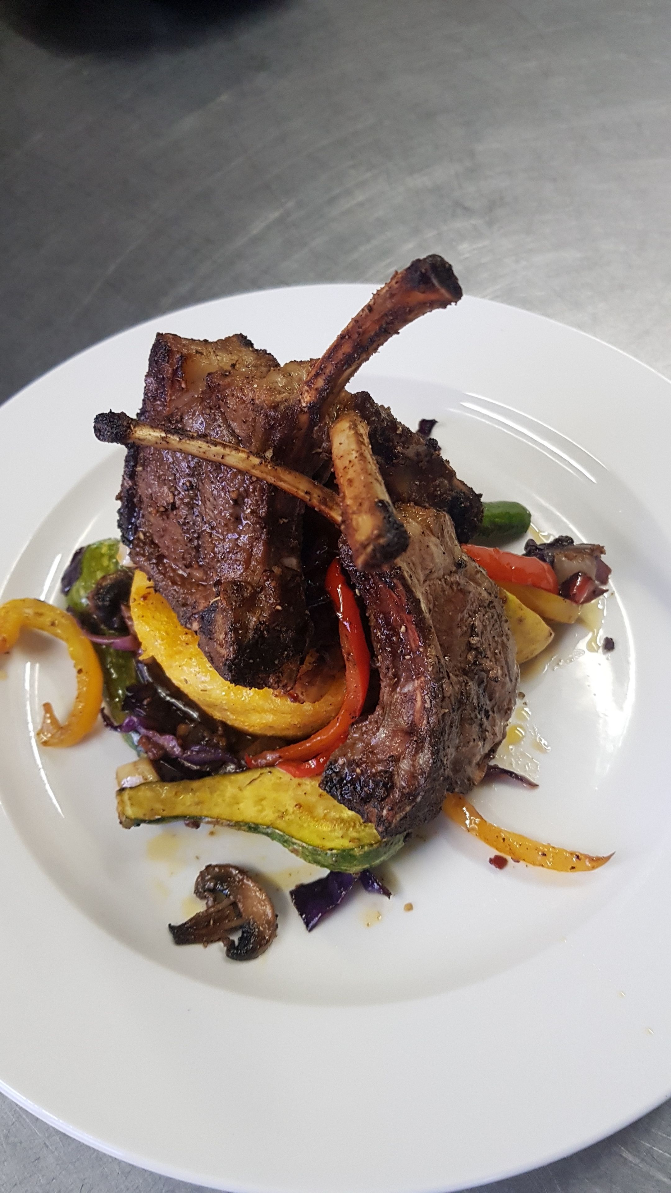 A plate of food with grilled lamb chops and vegetables.