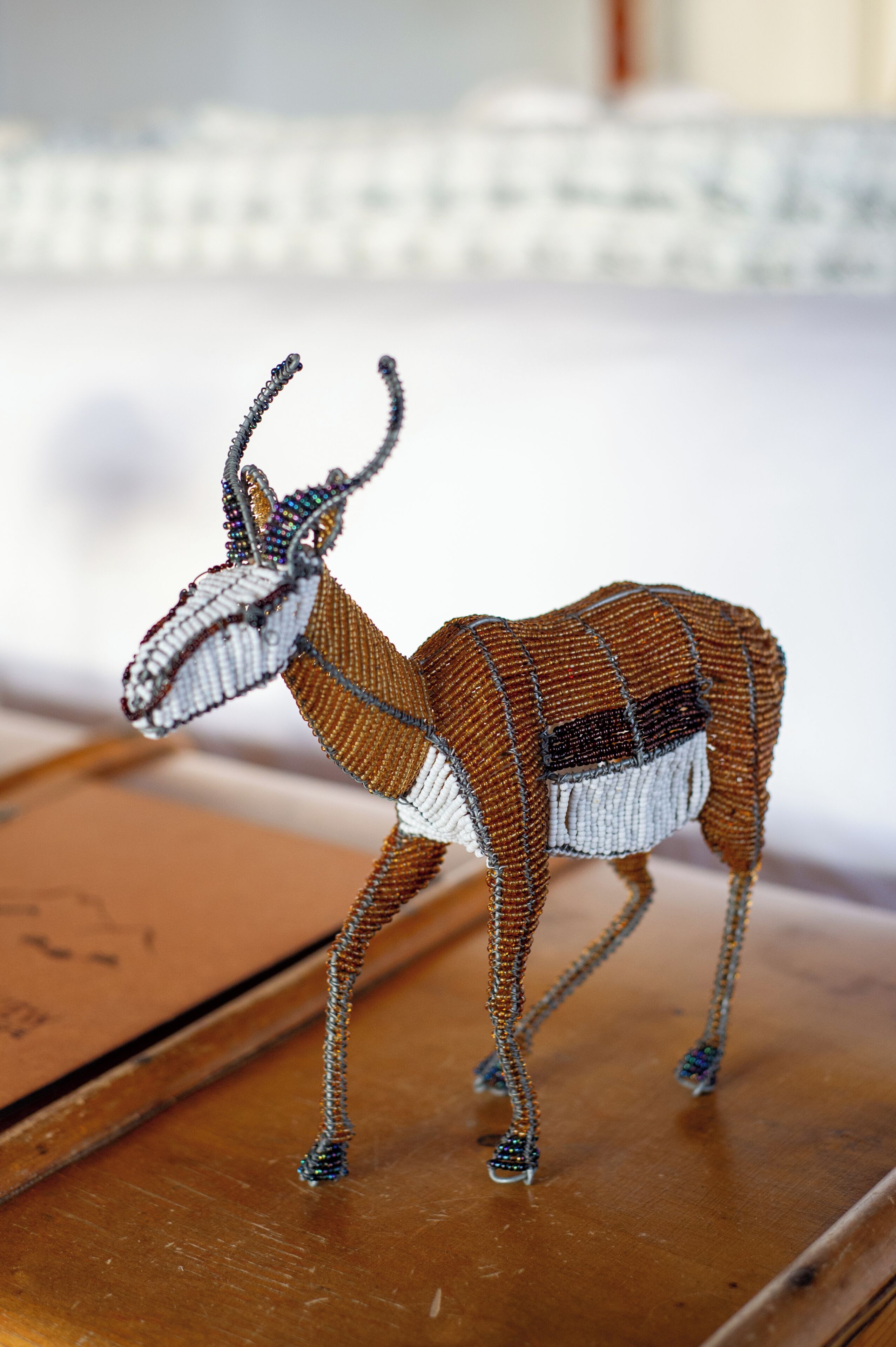 A beaded animal figure on a wooden surface.