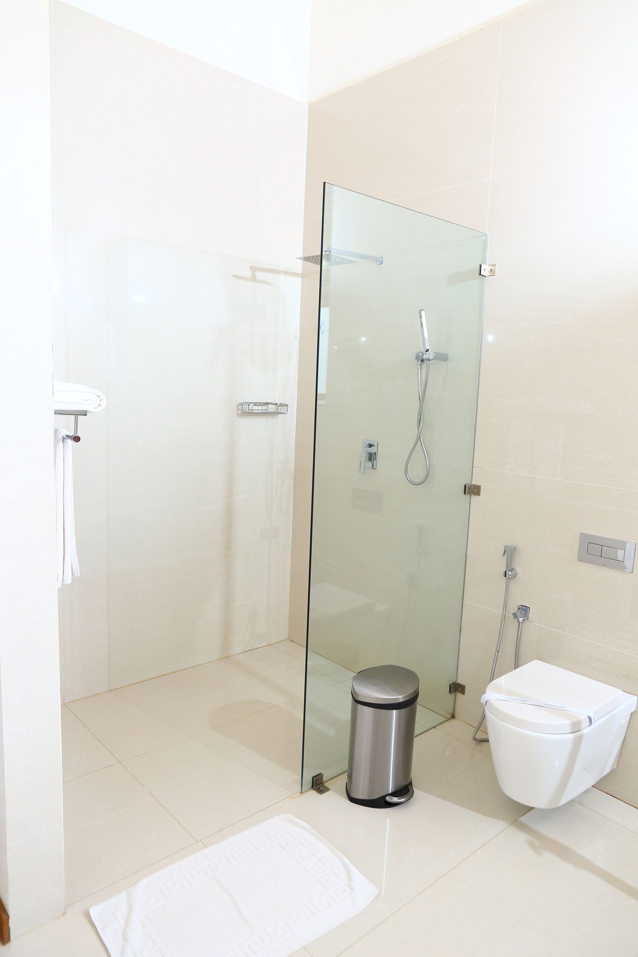 A modern bathroom with a glass-enclosed shower, a white toilet, and a trash bin.