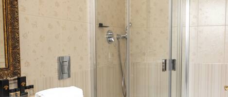 A bathroom with a glass-enclosed shower, a toilet, and a sink with a towel on the counter.