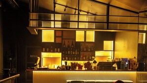 Una zona de bar con mostrador, asientos y una persona sentada.
