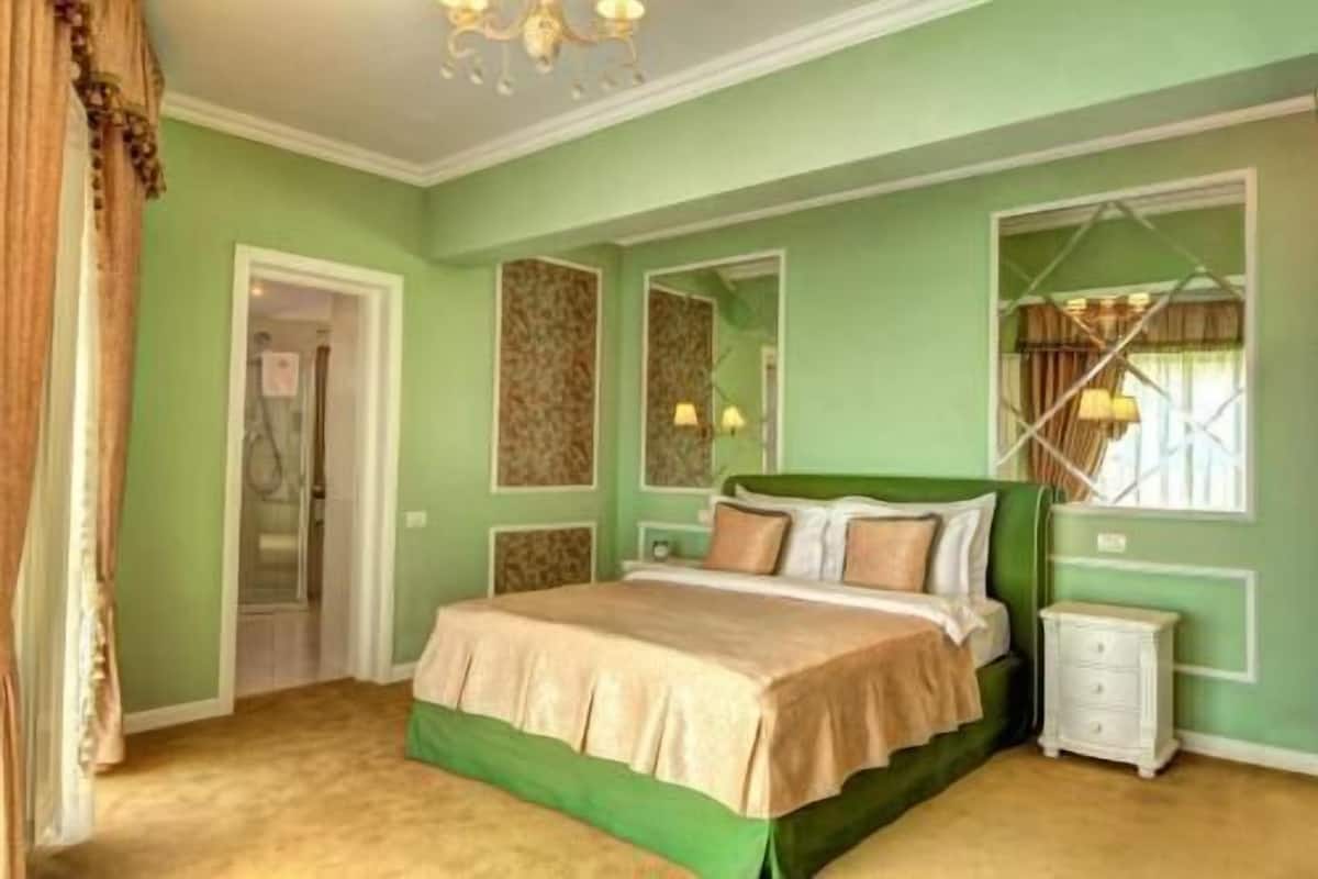 Ein Schlafzimmer mit Bett, Nachttischen, einem Spiegel und einem Fenster mit Vorhängen.