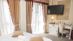 Una habitación de hotel con una cama, un escritorio, una silla, un televisor y cortinas.