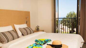 Habitación de hotel con una cama grande, un balcón con vistas y una mesita con una planta.