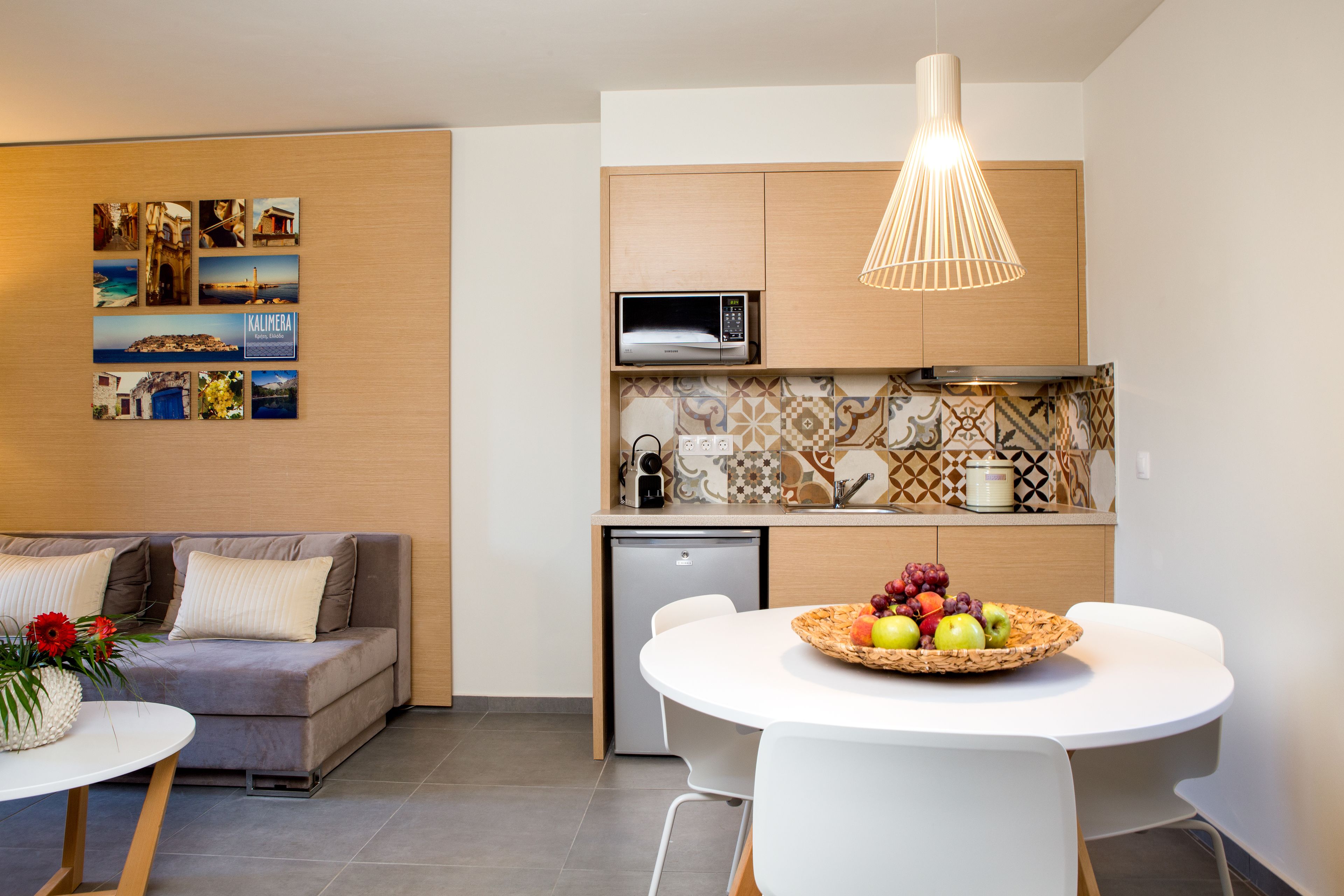A modern kitchen with a microwave, dishwasher, and a dining area with a basket of fruit.