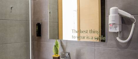A modern bathroom with a large mirror, a white sink, and a hairdryer mounted on the wall.