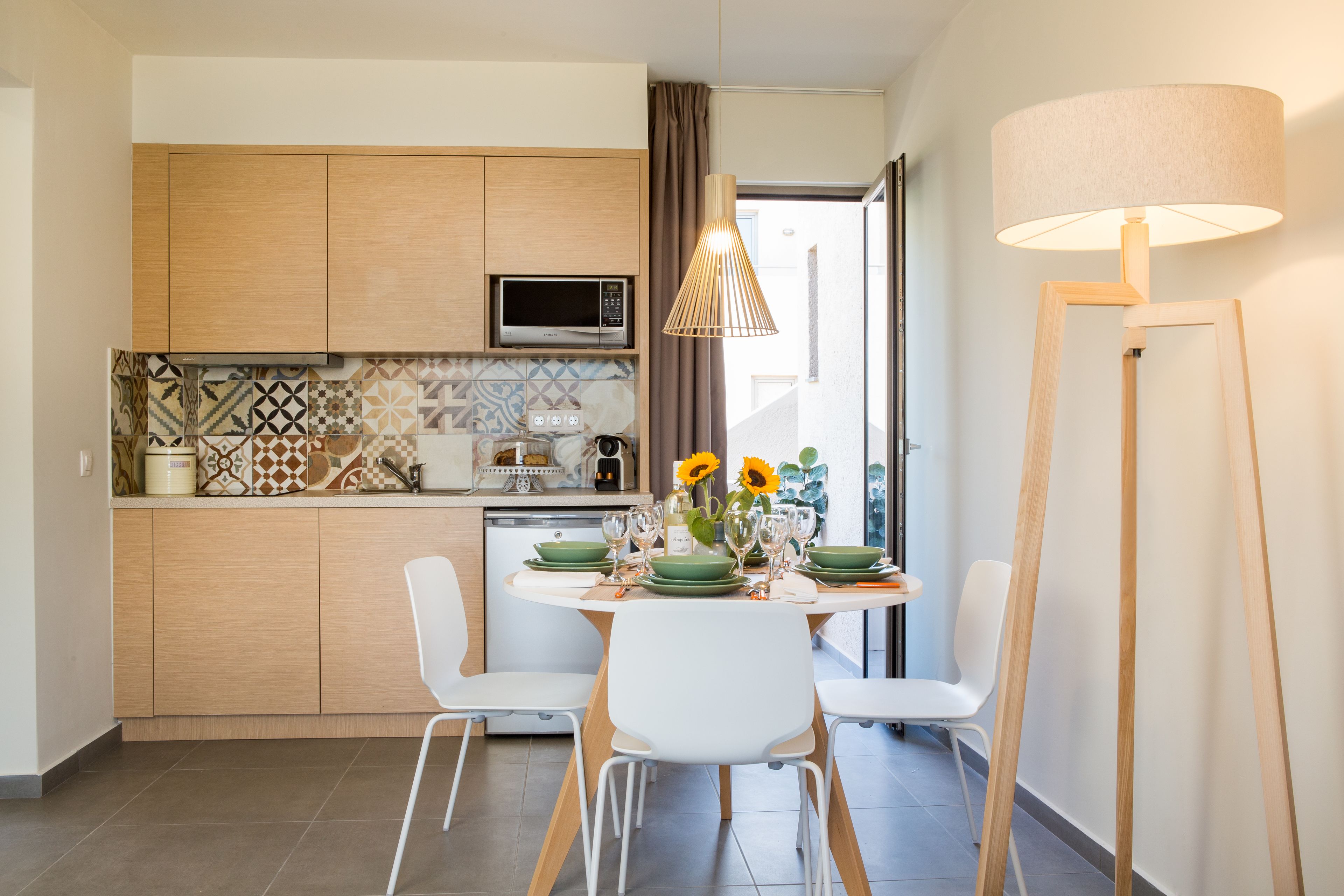 A modern kitchen with wooden cabinets, a microwave, and a dining area with a table set for two.