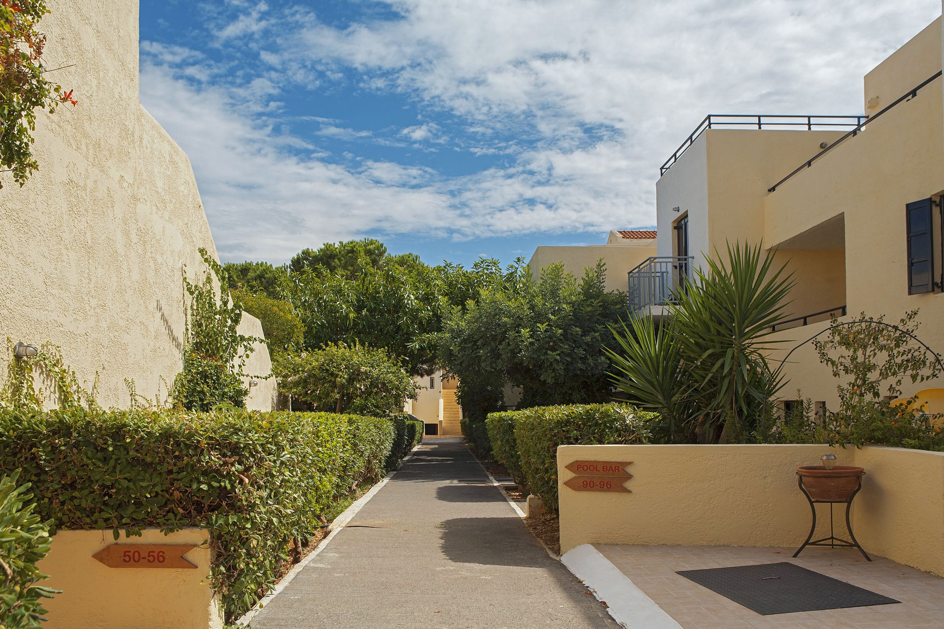 A narrow pathway flanked by buildings with signage indicating pool bar locations.